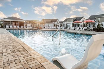 a large pool with chairs and umbrellas at the resort on a sunny day